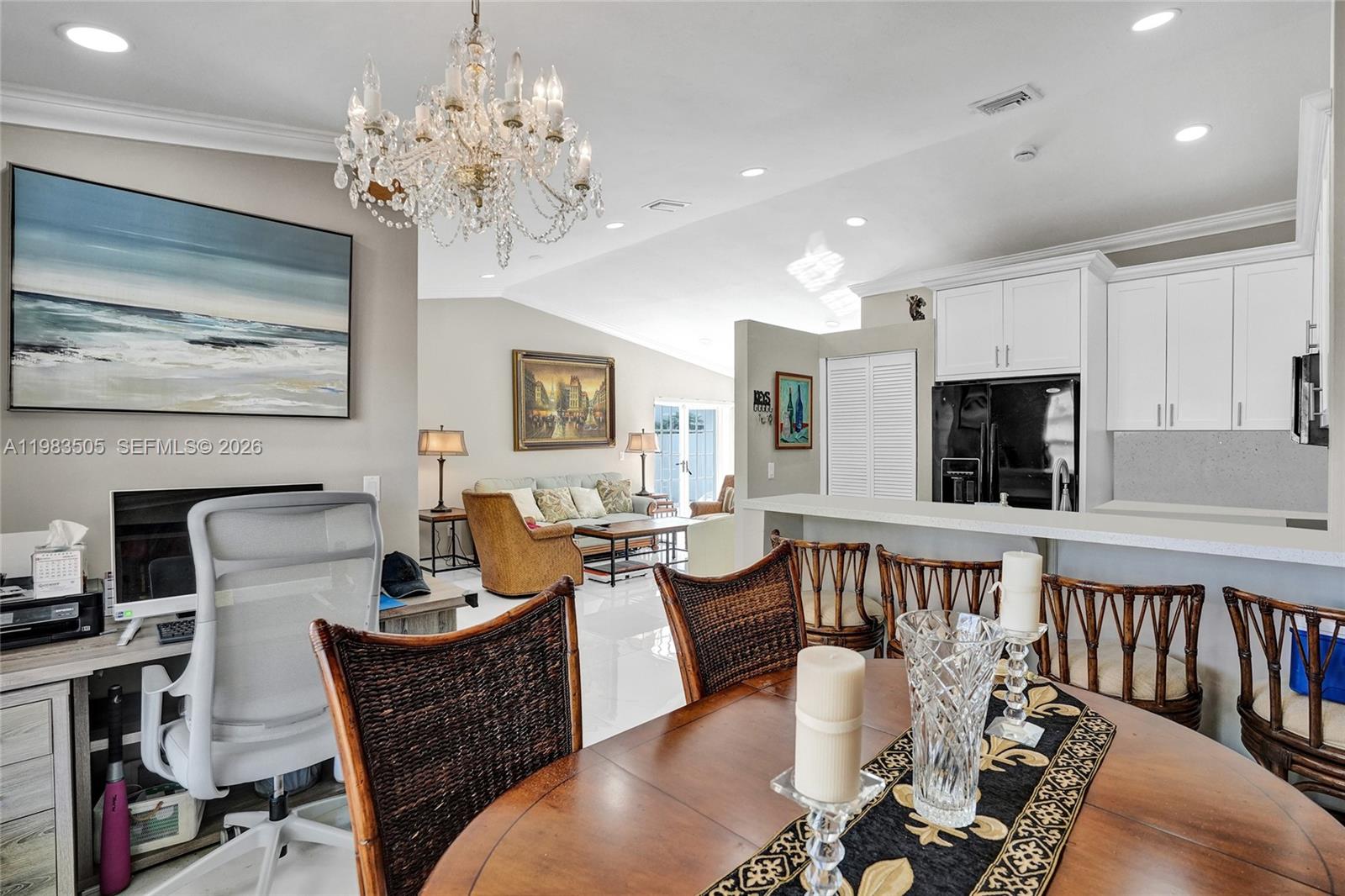 An open-concept living and dining area features a chandelier, white cabinetry, and rattan furniture — 6405 SW 152nd Cir Pl # 05, Miami FL 33193, MIAMI, FL