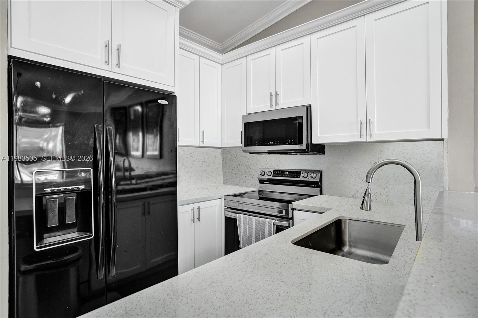A kitchen features white cabinets, a black refrigerator, stainless steel appliances, and speckled countertops — 6405 SW 152nd Cir Pl # 05, Miami FL 33193, MIAMI, FL