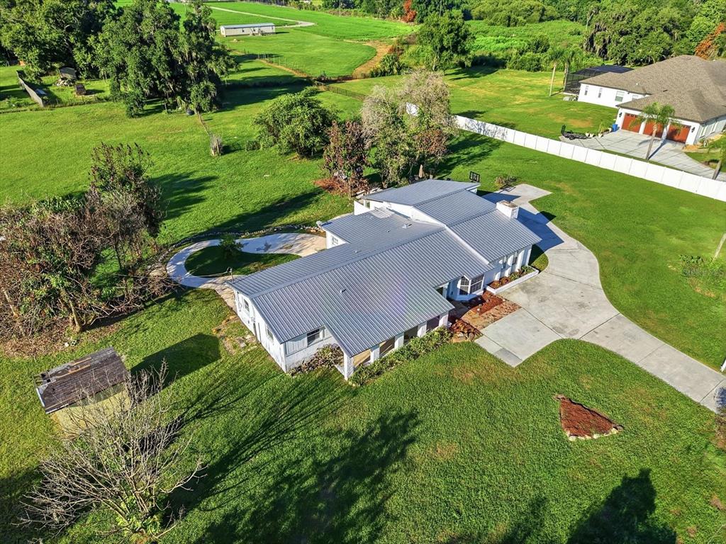 An aerial view shows a single-story house with a metal roof and a concrete driveway — 1113 COLSON ROAD, PLANT CITY, FL