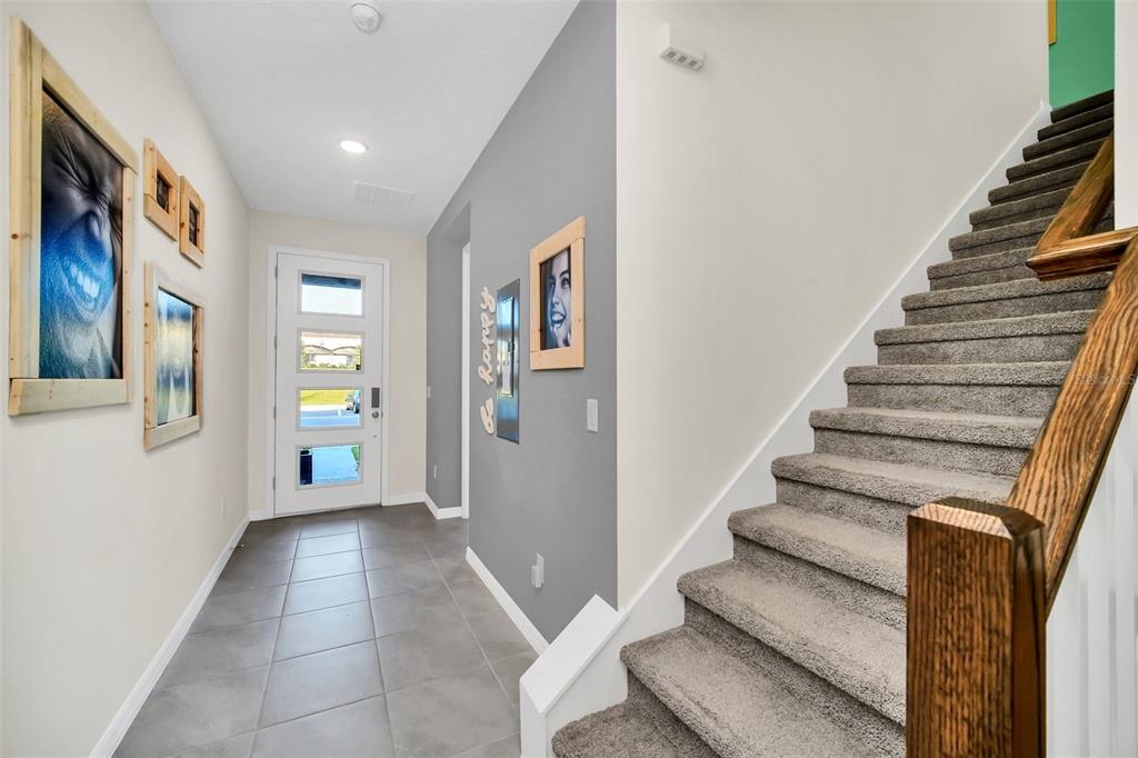 An entryway features gray tile flooring, a staircase with carpeted steps, and a white door — 1672 TROPICAL PALMS CIRCLE, KISSIMMEE, FL