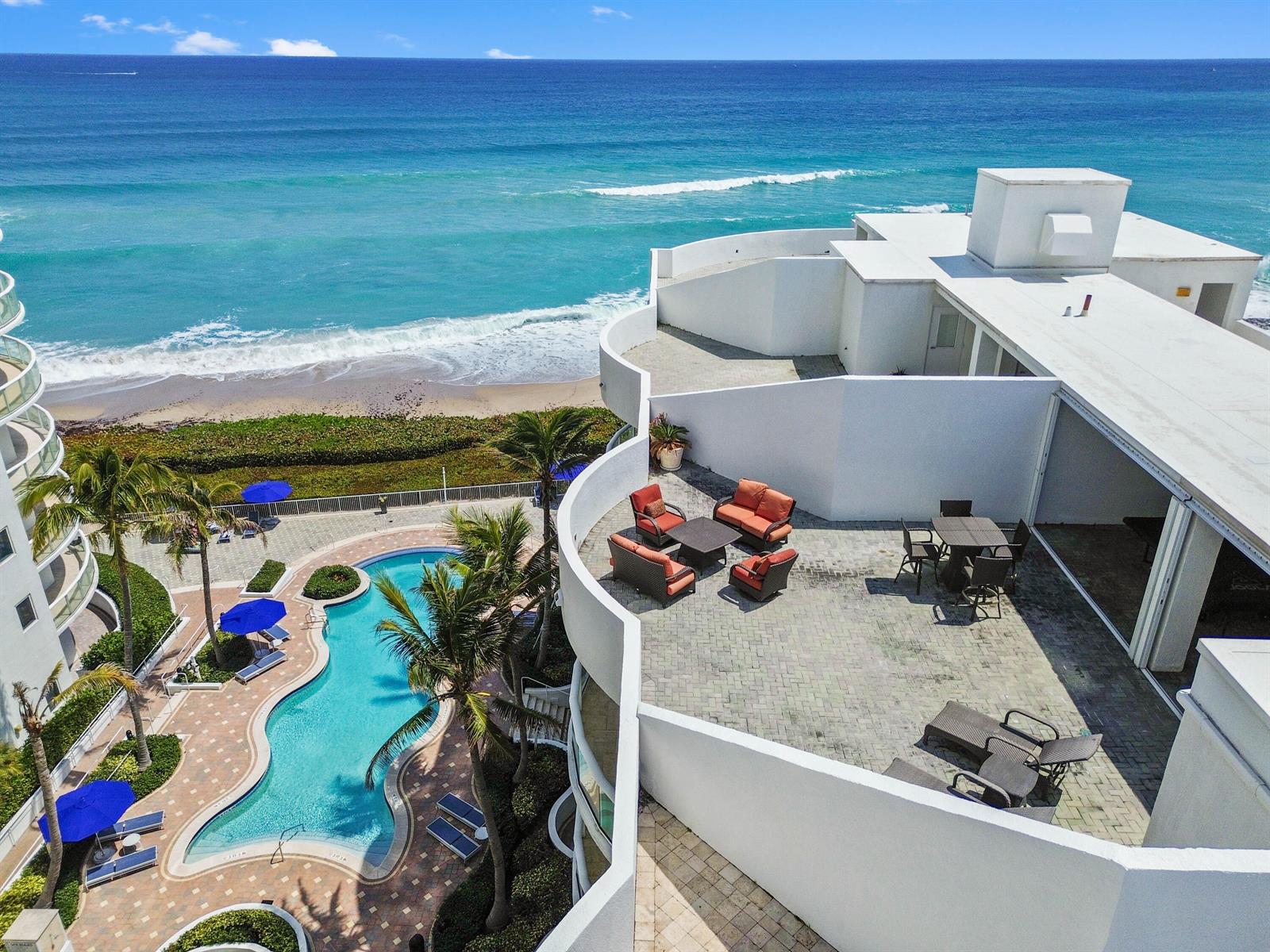 An aerial view shows a white building with a large patio overlooking a swimming pool — 4600 N Ocean Drive # 605, Riviera Beach FL 33404, RIVIERA BEACH, FL