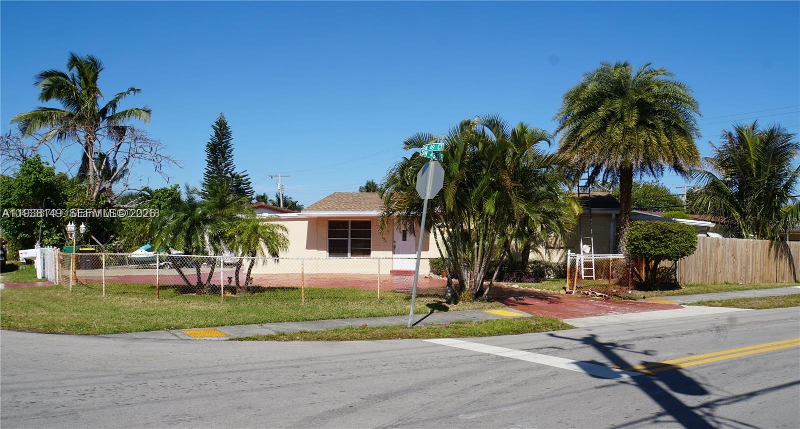 A single-story house with a fenced front yard and palm trees sits on a corner lot — 4361 SW 49th Ct, Dania Beach FL 33314, DANIA BEACH, FL