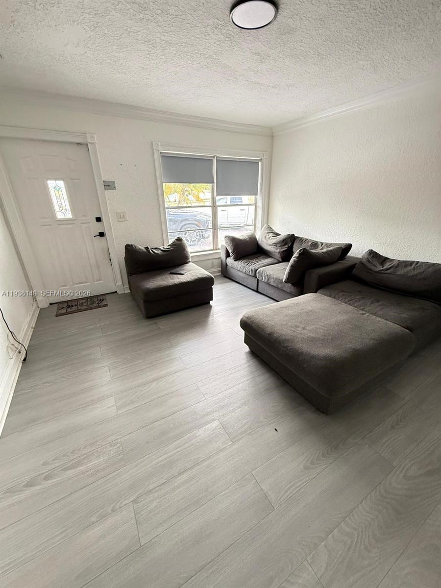 A living room features light wood-look flooring, white walls, and a modular gray sofa — 4361 SW 49th Ct, Dania Beach FL 33314, DANIA BEACH, FL