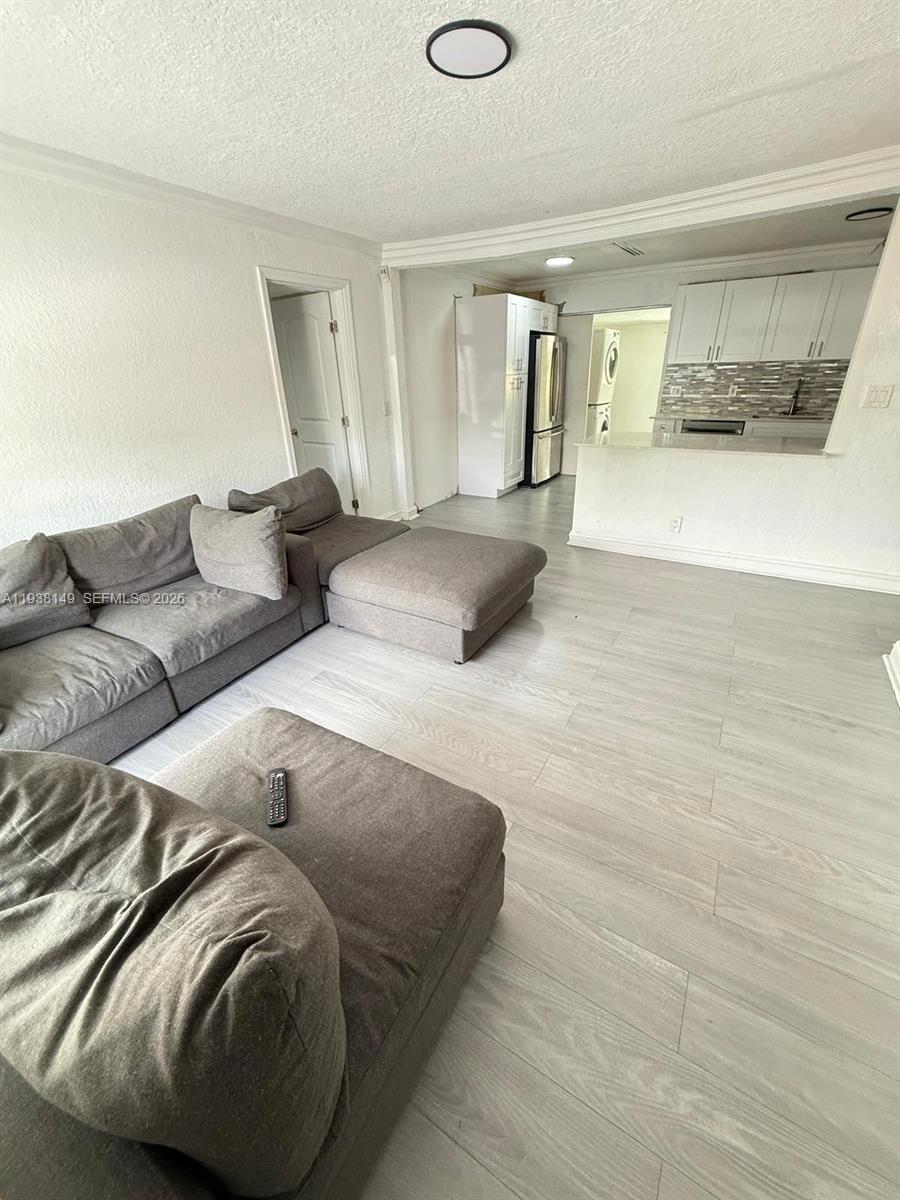 A living room features gray sectional seating, light wood-look flooring, and an open kitchen beyond — 4361 SW 49th Ct, Dania Beach FL 33314, DANIA BEACH, FL