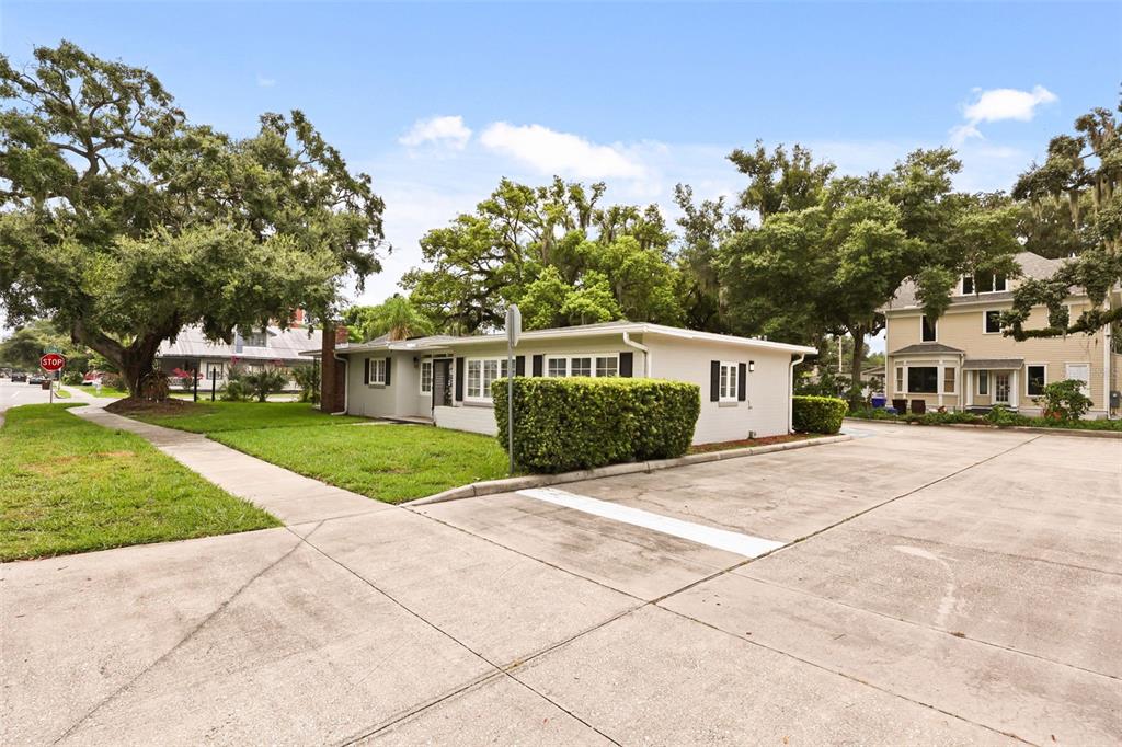 A single-story light-colored building with a large hedge and a concrete parking area — 104 S CLYDE AVENUE, KISSIMMEE, FL