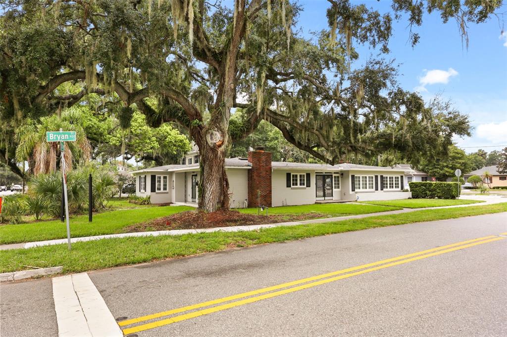 A single-story house with a brick chimney sits behind a large oak tree — 104 S CLYDE AVENUE, KISSIMMEE, FL