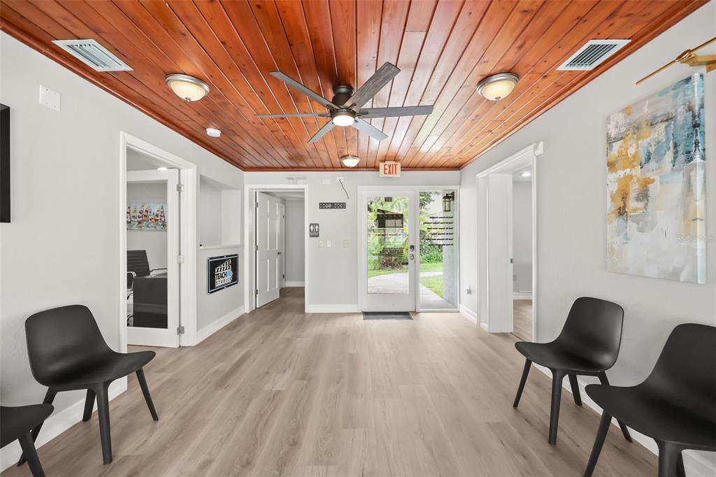 A waiting room features light wood flooring, a wood-paneled ceiling, and several black chairs — 104 S CLYDE AVENUE, KISSIMMEE, FL