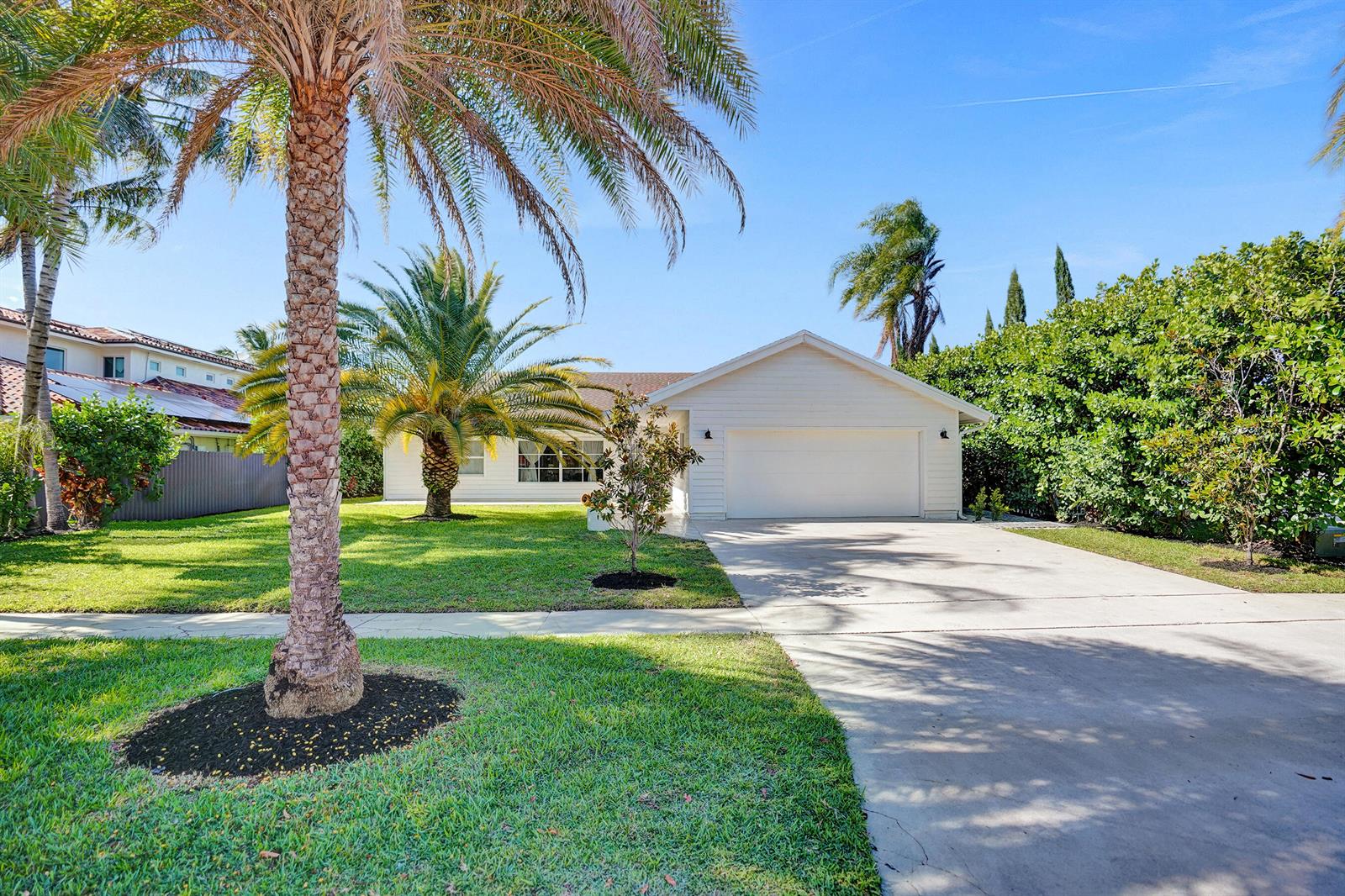 A single-story white house features a two-car garage, a concrete driveway, and palm trees — 271 Oregon Lane, Boca Raton FL 33487, BOCA RATON, FL