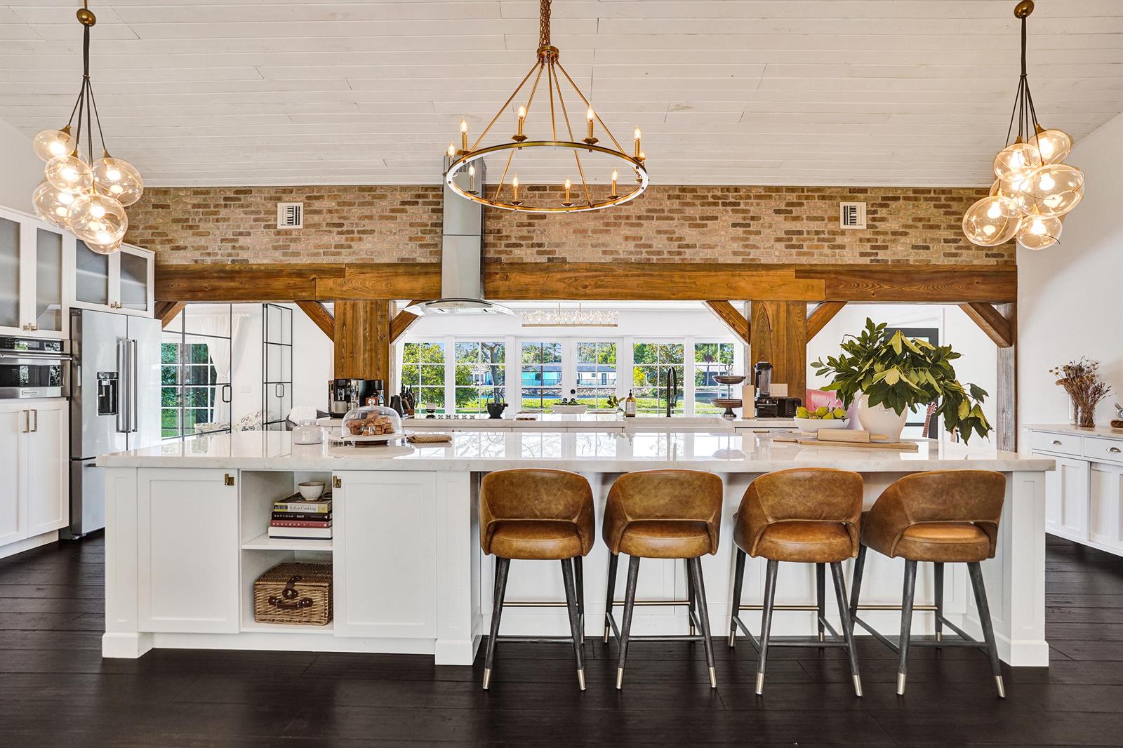 A kitchen features a large white island with leather barstools, brick walls, and wooden beams — 271 Oregon Lane, Boca Raton FL 33487, BOCA RATON, FL