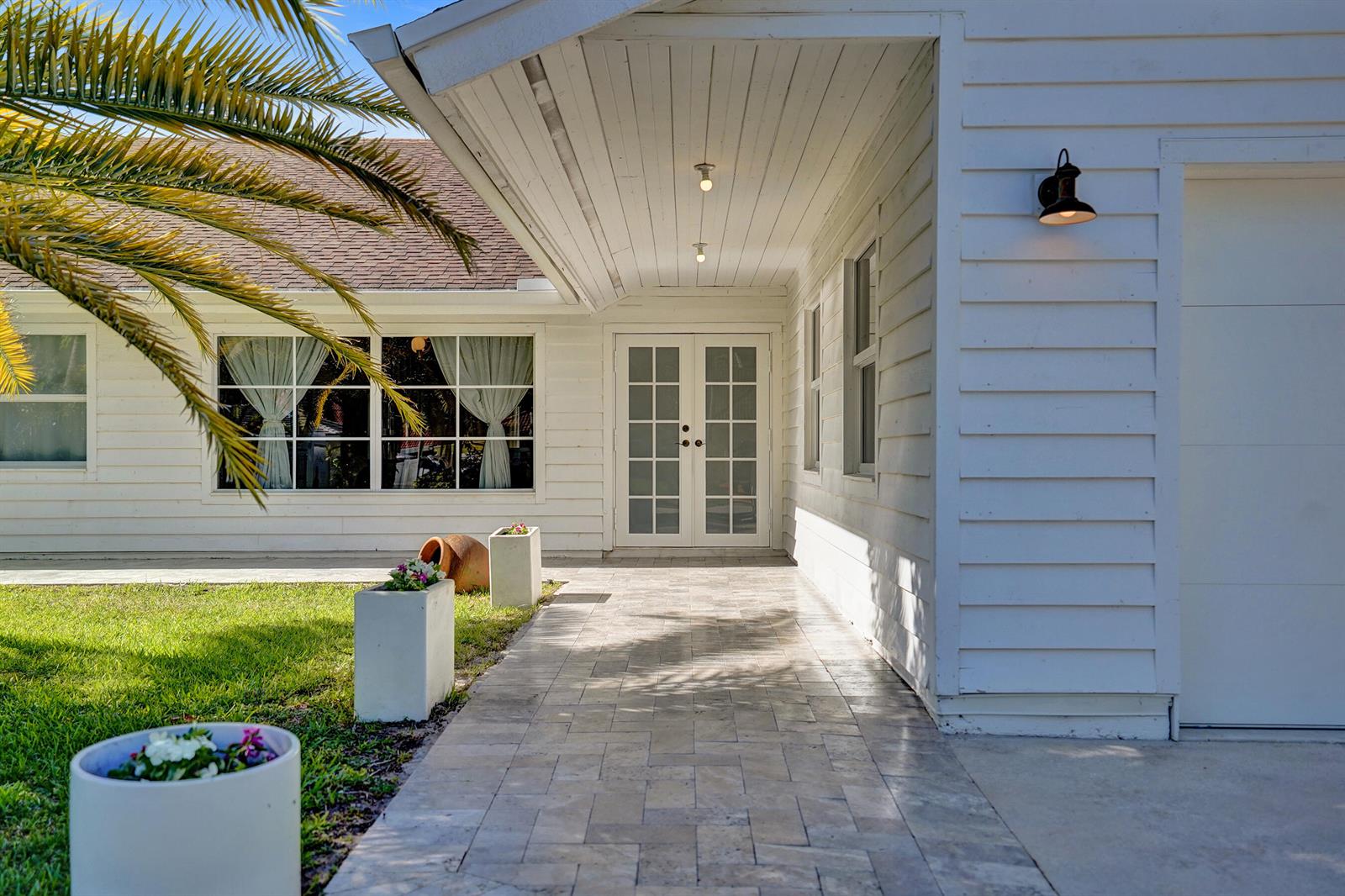 A white house exterior features a stone walkway leading to double glass doors under a porch — 271 Oregon Lane, Boca Raton FL 33487, BOCA RATON, FL