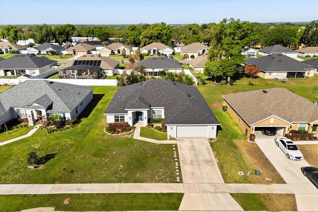 An aerial view shows a suburban single-story house with a dark shingled roof and driveway — 345 ASHTON WOODS LANE, LEESBURG, FL