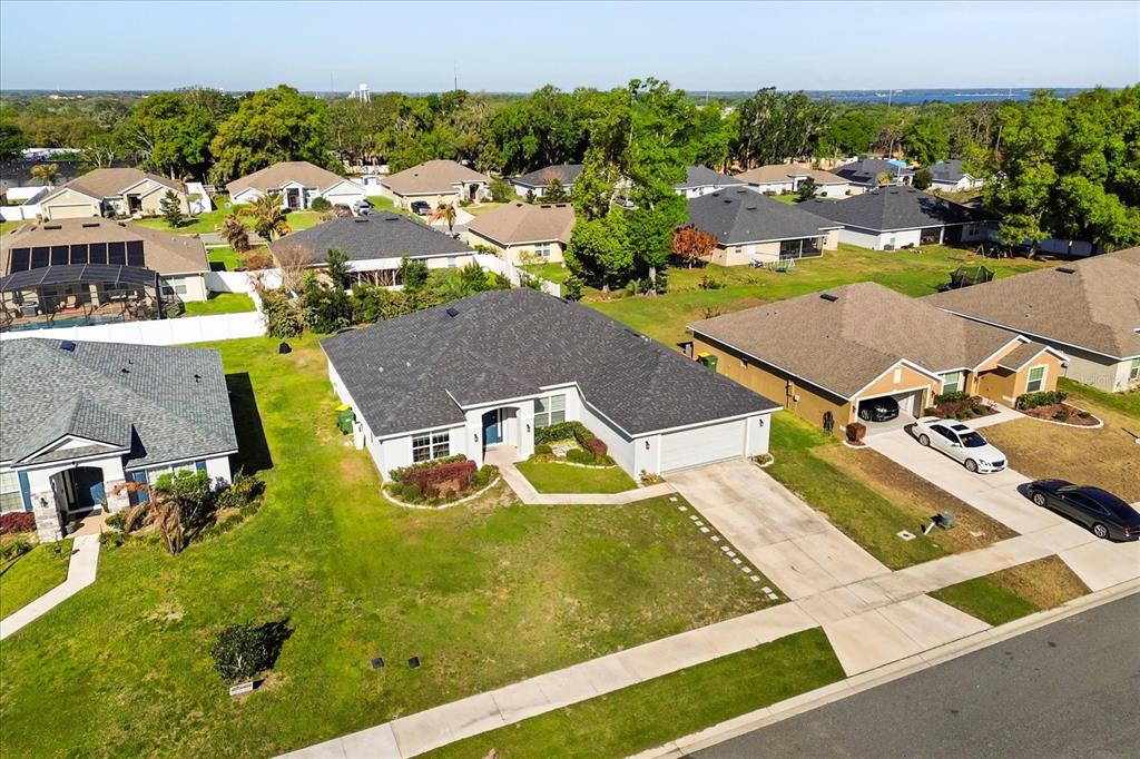 An aerial view shows a single-story suburban house with a gray roof and driveway — 345 ASHTON WOODS LANE, LEESBURG, FL