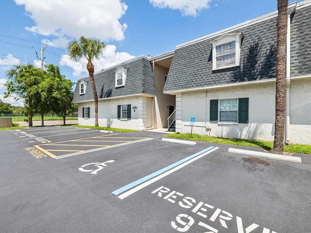 A two-story apartment building features a parking lot with a designated handicap space — 4335 AEGEAN DRIVE UNIT 128A, TAMPA, FL