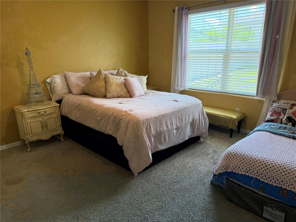 A bedroom features a queen bed, a twin bed, and a nightstand with an Eiffel tower — 6524 CORAL BERRY DRIVE, MOUNT DORA, FL