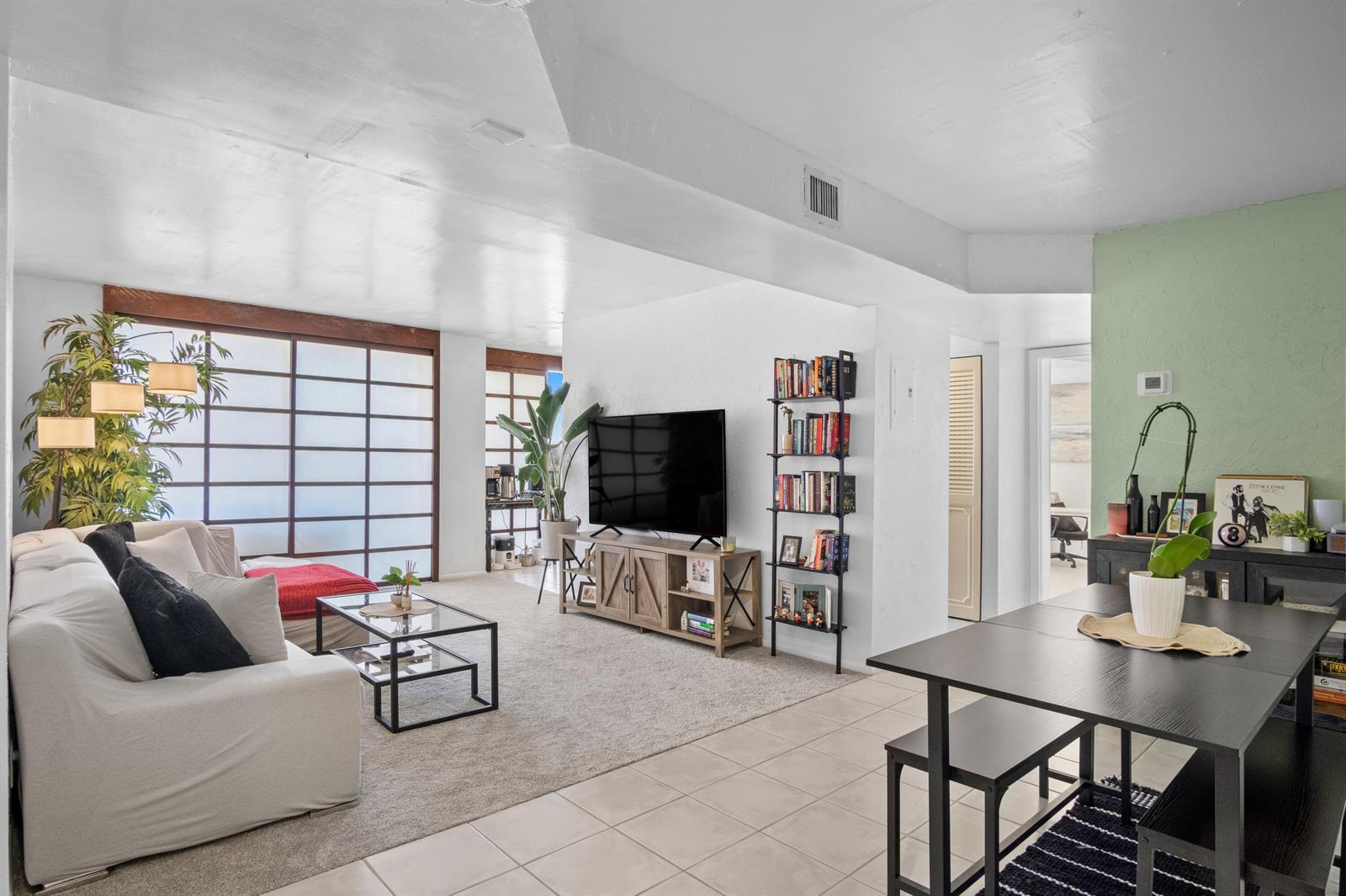A living room and dining area with a white sofa, television, and tile flooring — 3500 Blue Lake Drive # 503, Pompano Beach FL 33064, POMPANO BEACH, FL