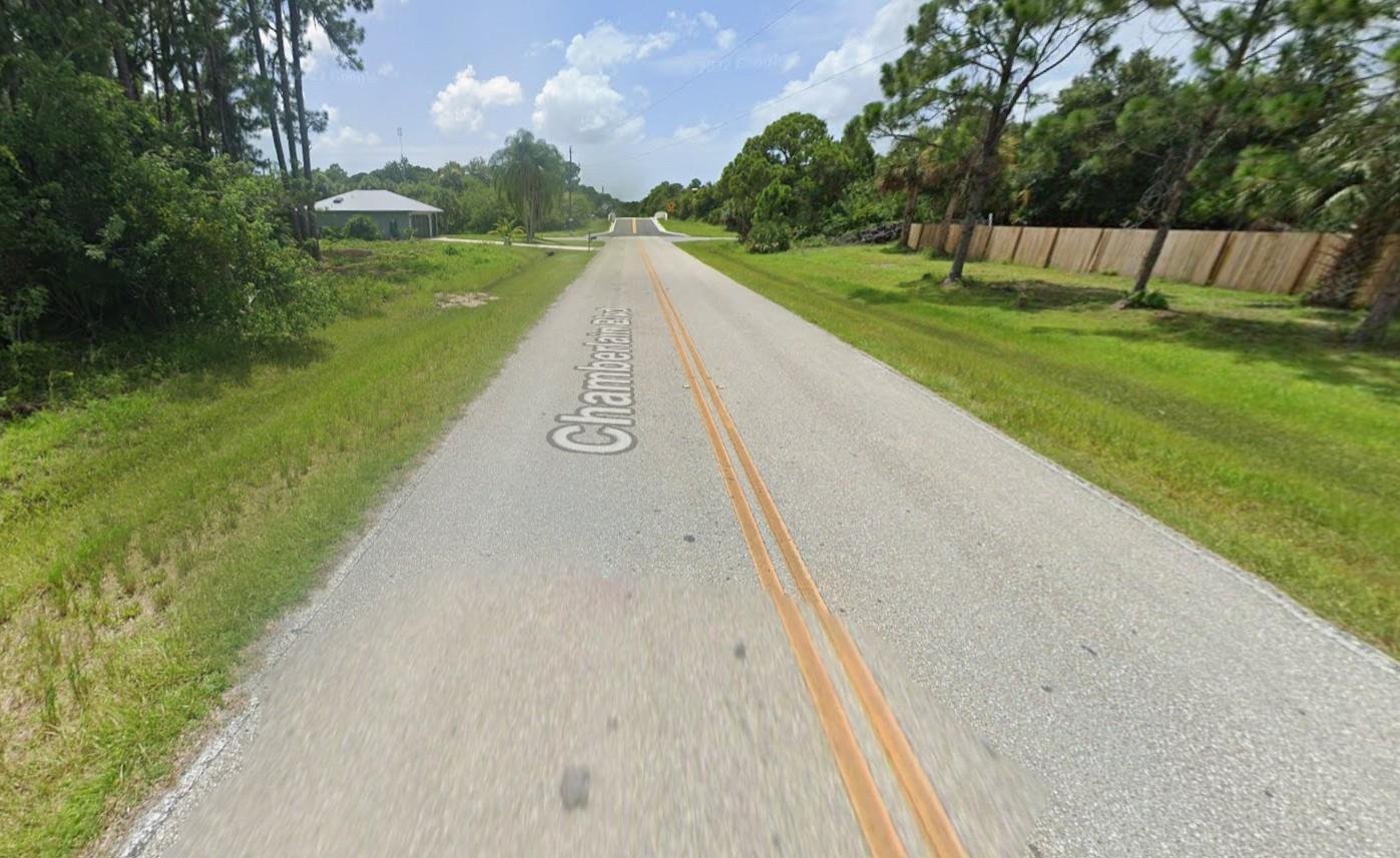 A paved road with double yellow lines stretches toward a bridge in a rural area — 12203 Chamberlain Boulevard, FL 33953, FL