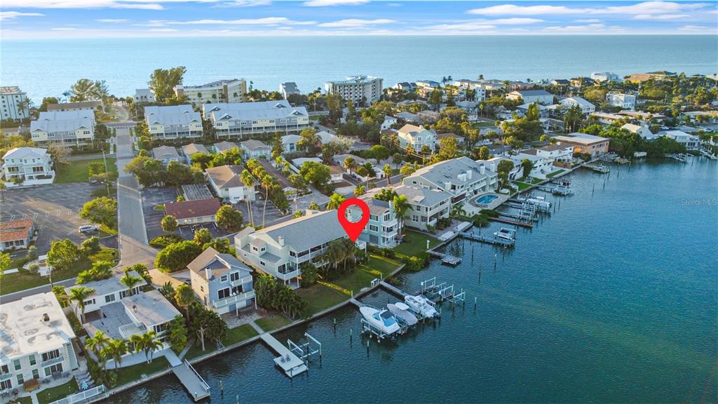 An aerial view shows a waterfront residential building with a boat dock and pool — 2505 BAY BOULEVARD UNIT 1, INDIAN ROCKS BEACH, FL