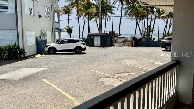 A parking lot with two cars sits in front of a building near palm trees — PLAYA AZUL OCEAN DRIVE UNIT 748, LUQUILLO, PR