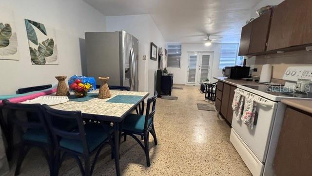 A dining area with a tiled table and chairs sits next to a kitchen with appliances — PLAYA AZUL OCEAN DRIVE UNIT 748, LUQUILLO, PR