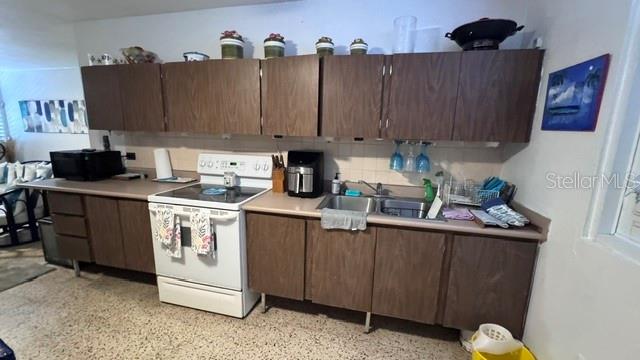 A kitchen features dark wood cabinets, a white stove, and a stainless steel sink — PLAYA AZUL OCEAN DRIVE UNIT 748, LUQUILLO, PR