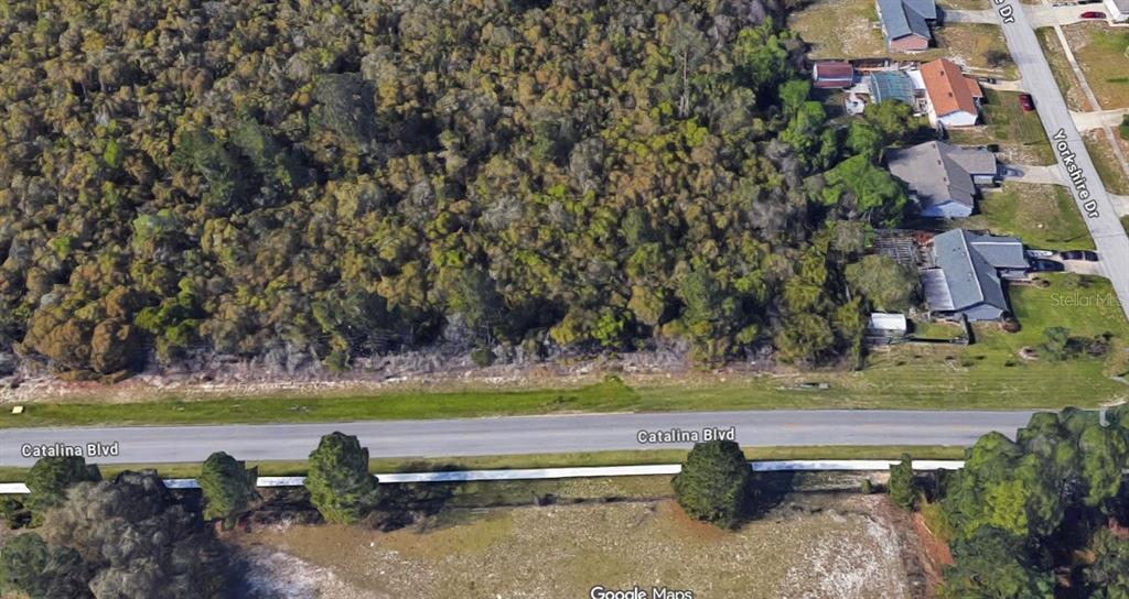 An aerial view shows a wooded lot situated along a paved road — SIXMA ROAD, DELTONA, FL