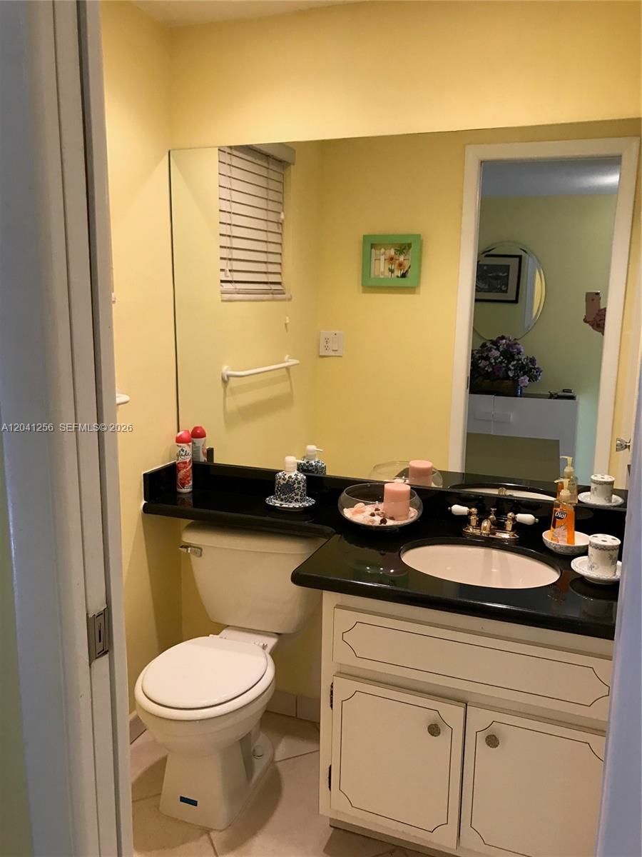 A bathroom features a black countertop, white vanity, toilet, and a large wall mirror — 3199 S Ocean Dr # 402, Hallandale Beach FL 33009, HALLANDALE BEACH, FL