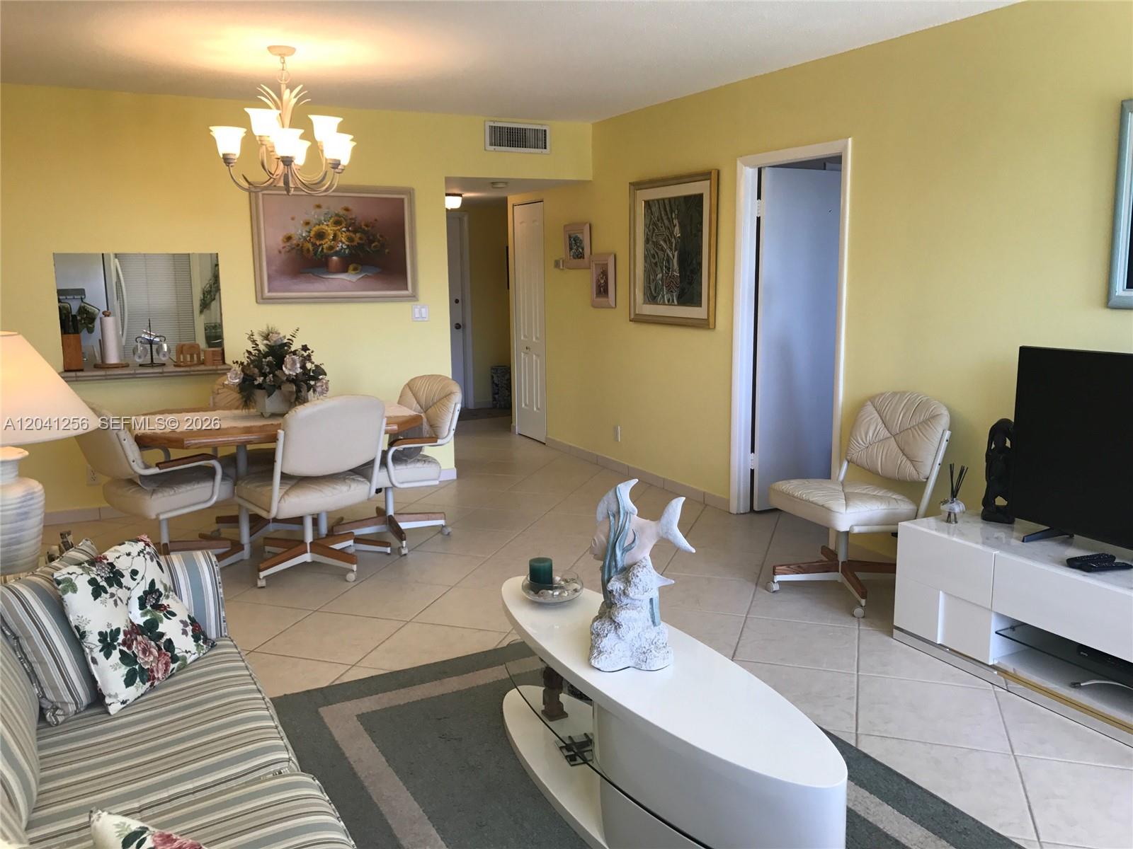 A living and dining area features yellow walls, tile flooring, and a white coffee table — 3199 S Ocean Dr # 402, Hallandale Beach FL 33009, HALLANDALE BEACH, FL