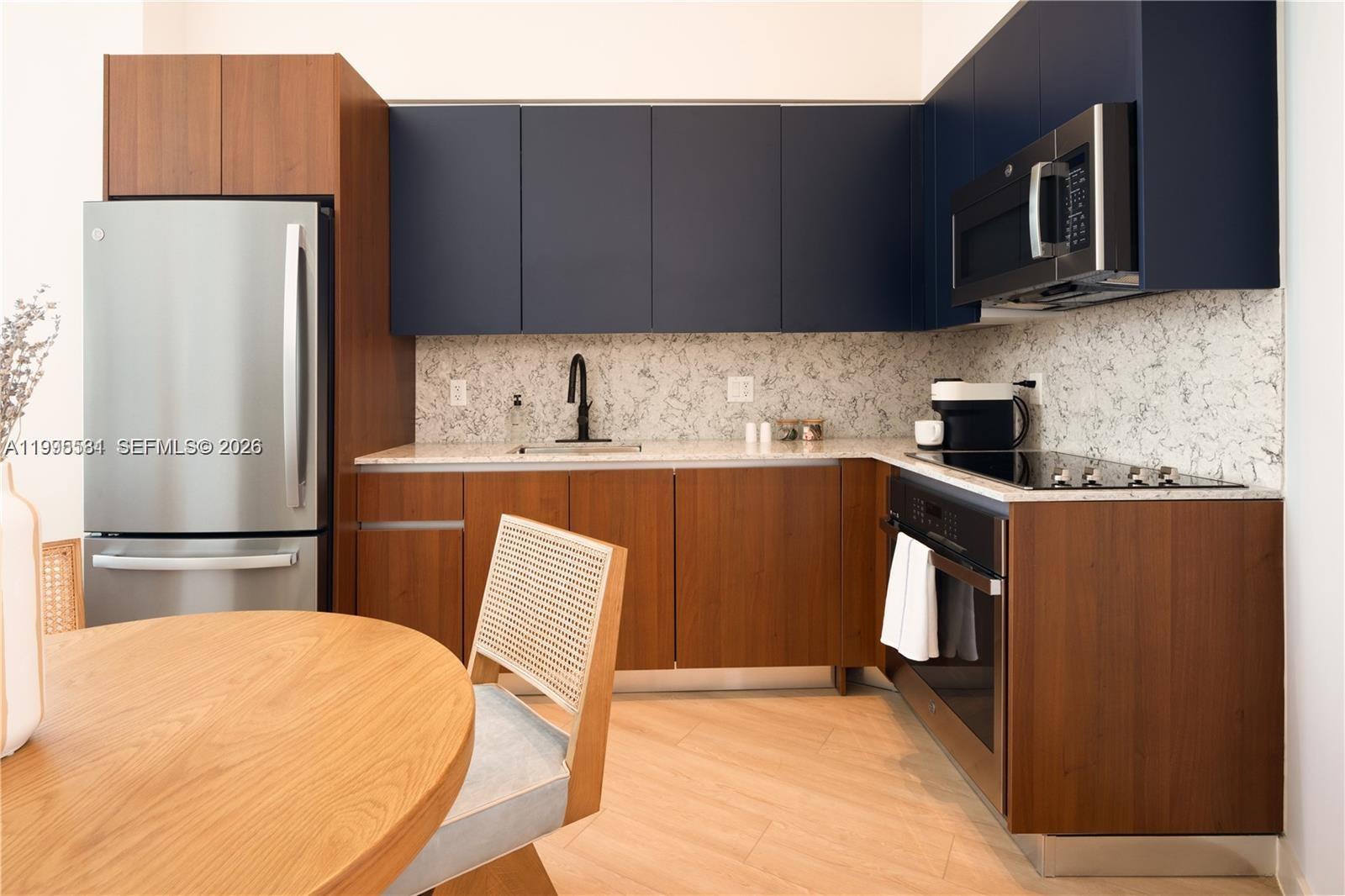 A modern kitchen features dark blue upper cabinets, wood lower cabinets, and marble-patterned countertops — 275 SW 6th St # 502, Miami FL 33130, MIAMI, FL