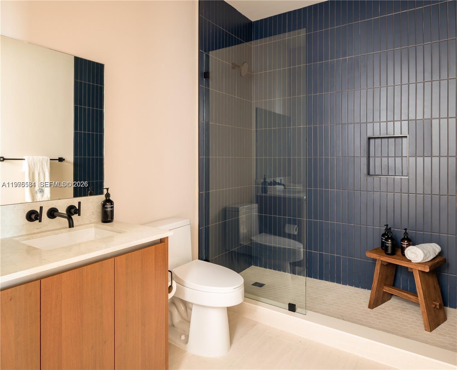 A modern bathroom features a wood vanity, a white toilet, and a blue-tiled walk-in shower — 275 SW 6th St # 502, Miami FL 33130, MIAMI, FL
