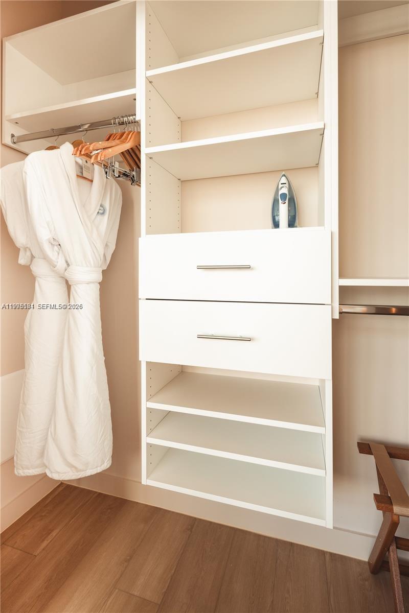 A white closet features open shelving, two drawers, a hanging rod, and a white robe — 275 SW 6th St # 502, Miami FL 33130, MIAMI, FL