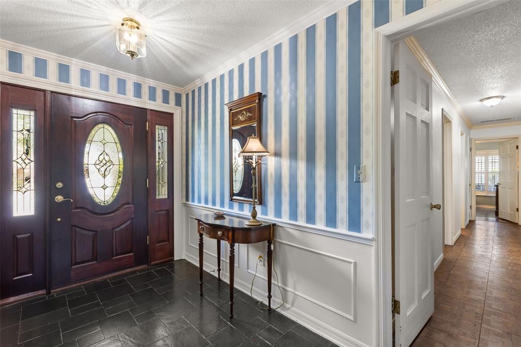 An entryway features a dark wood door, blue striped wallpaper, wainscoting, and black tile flooring — 504 TIVOLI COURT, ALTAMONTE SPRINGS, FL