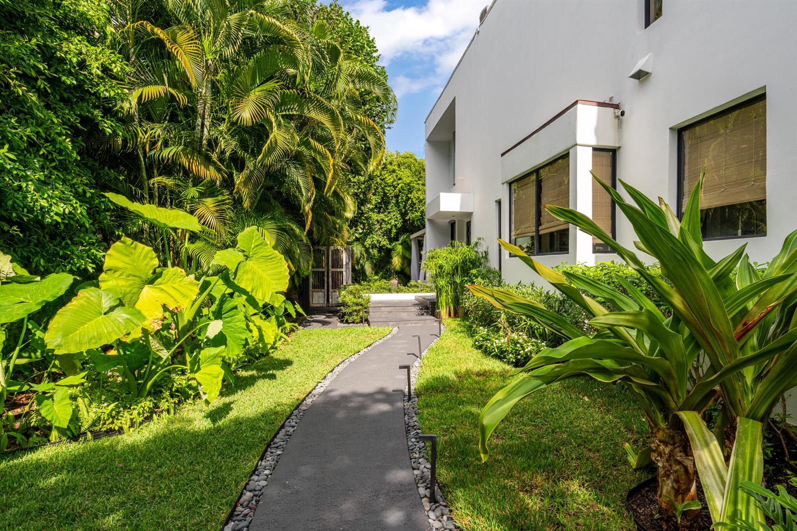A paved walkway leads through a lush garden toward the side of a white house — 423 Chilean Avenue, Palm Beach FL 33480, PALM BEACH, FL