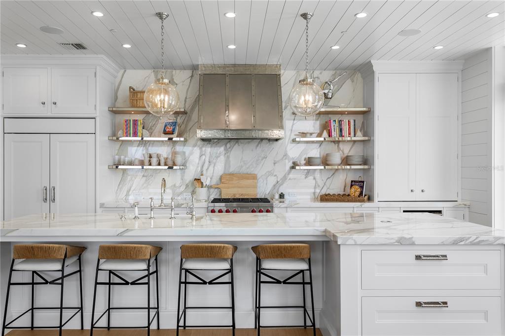 A modern kitchen features a marble island, white cabinetry, open shelving, and a metal range hood — 2103 BAYSHORE BOULEVARD UNIT 504, TAMPA, FL
