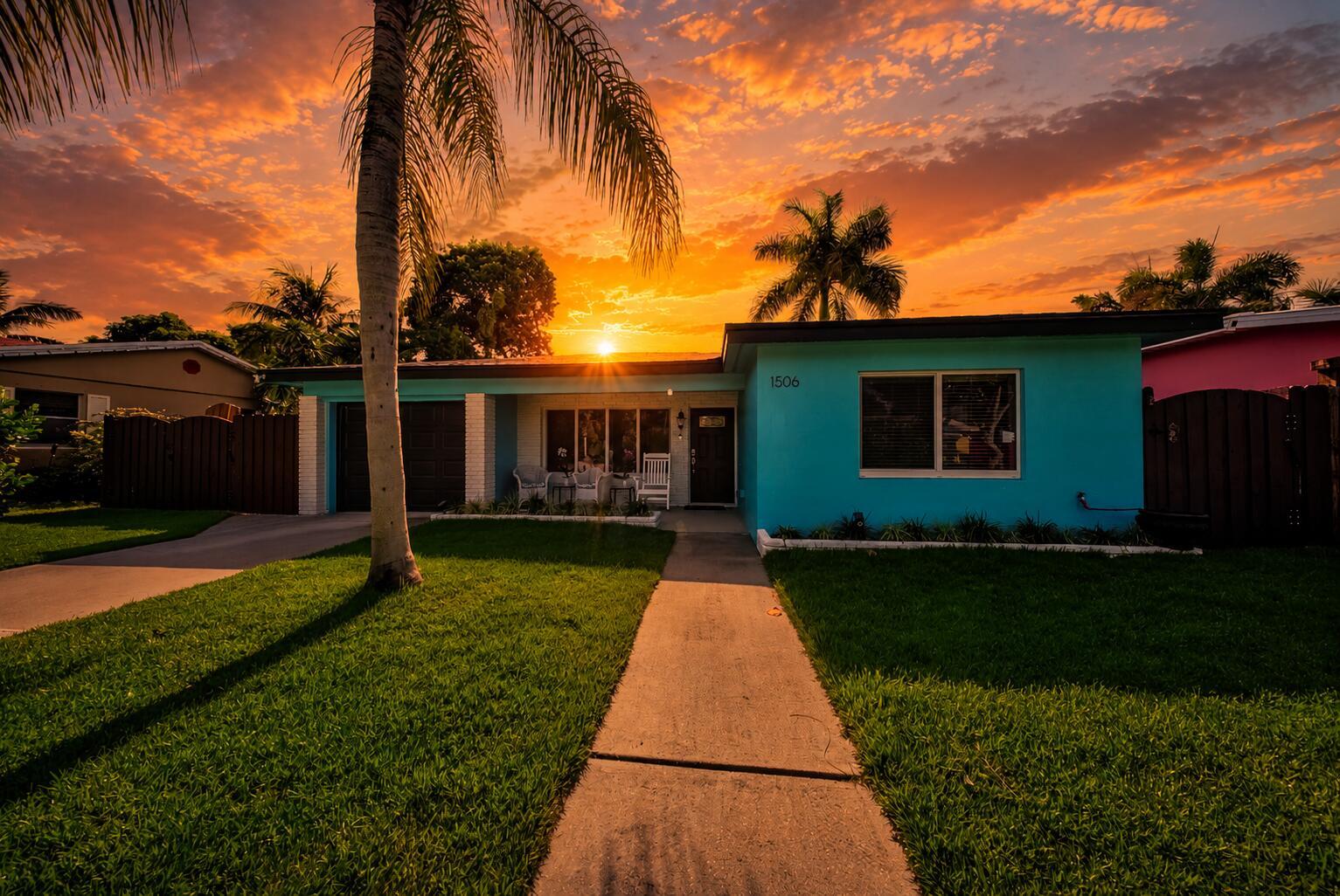 A bright blue single-story house with a palm tree and sunset sky in the background — 1506 N L Street, FL 33460, FL