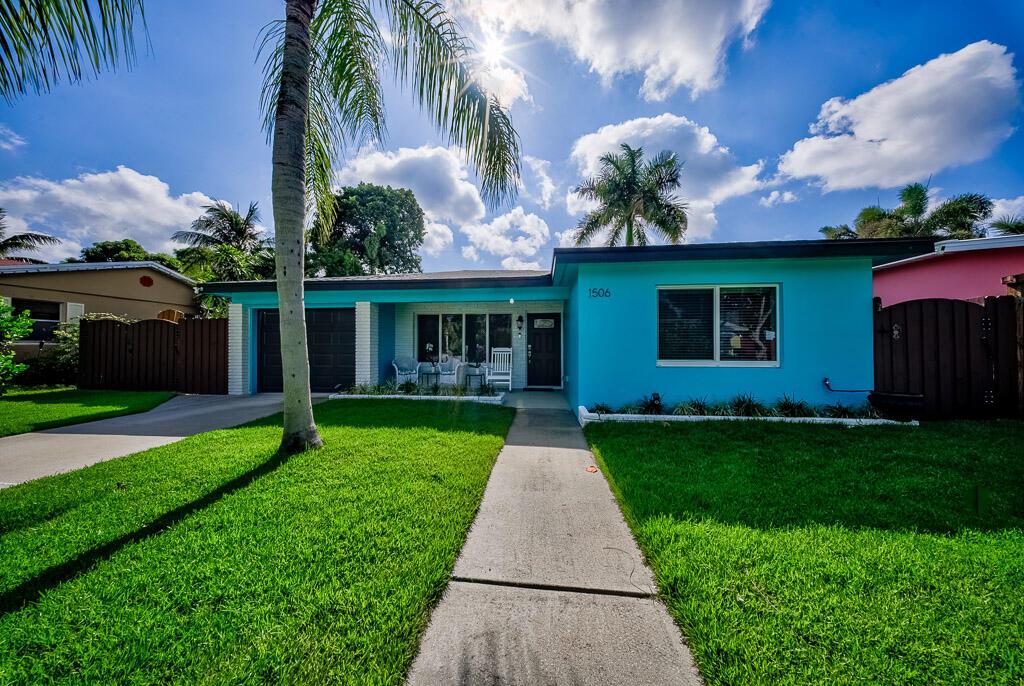 A bright blue single-story house features a palm tree, a concrete walkway, and a lawn — 1506 N L Street, FL 33460, FL