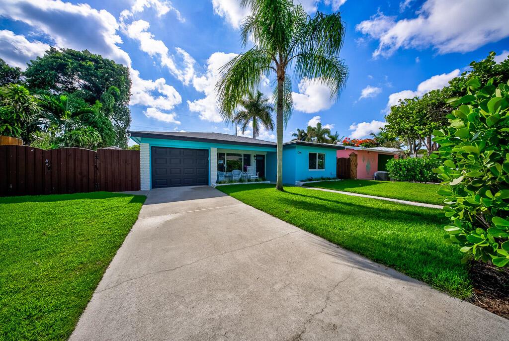 A bright blue single-story house with a concrete driveway, palm tree, and green lawn — 1506 N L Street, FL 33460, FL