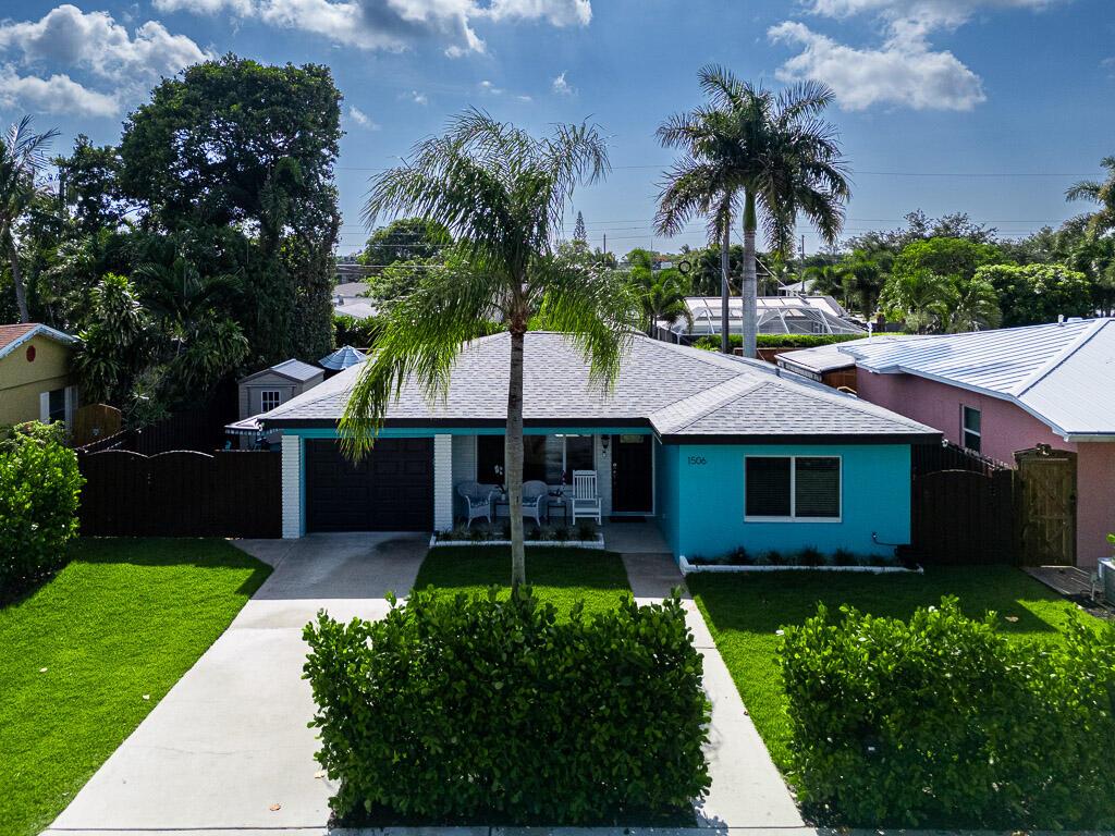 A bright blue single-story house with a palm tree and a concrete driveway in front — 1506 N L Street, FL 33460, FL