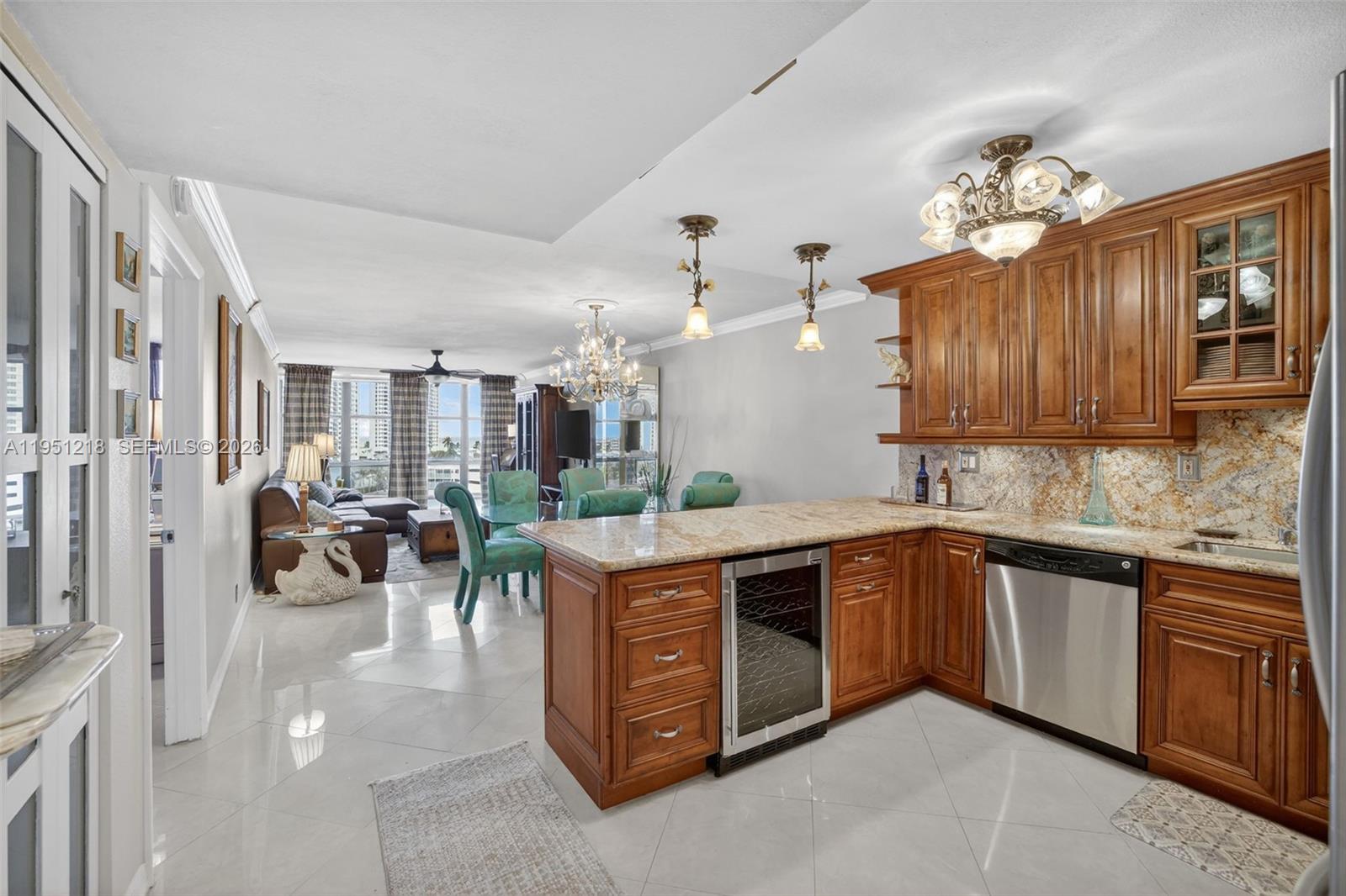 A kitchen with wood cabinets and granite countertops opens into a living and dining area — 1000 Parkview Dr # 806, Hallandale Beach FL 33009, HALLANDALE BEACH, FL