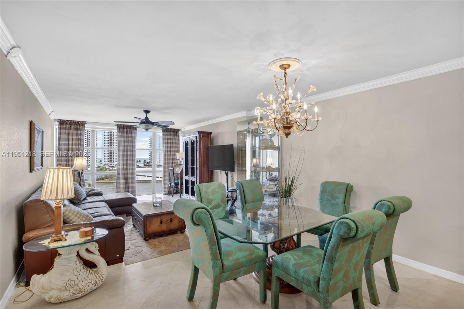 A dining area with a glass table and green chairs sits beside a living room — 1000 Parkview Dr # 806, Hallandale Beach FL 33009, HALLANDALE BEACH, FL