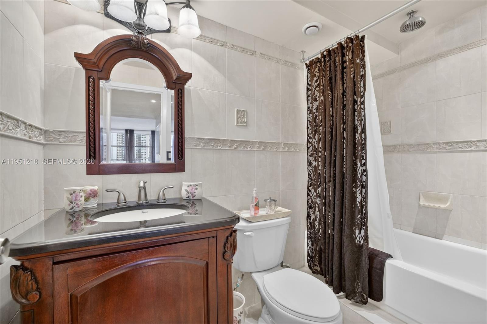 A bathroom features a dark wood vanity, a mirror, a toilet, and a shower-tub combo — 1000 Parkview Dr # 806, Hallandale Beach FL 33009, HALLANDALE BEACH, FL