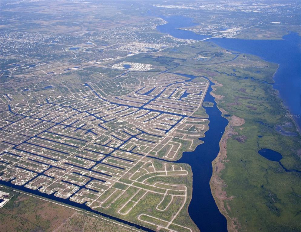 An aerial view shows a residential neighborhood with canal-front lots bordering a large waterway — 14615 LILLIAN CIRCLE, PORT CHARLOTTE, FL
