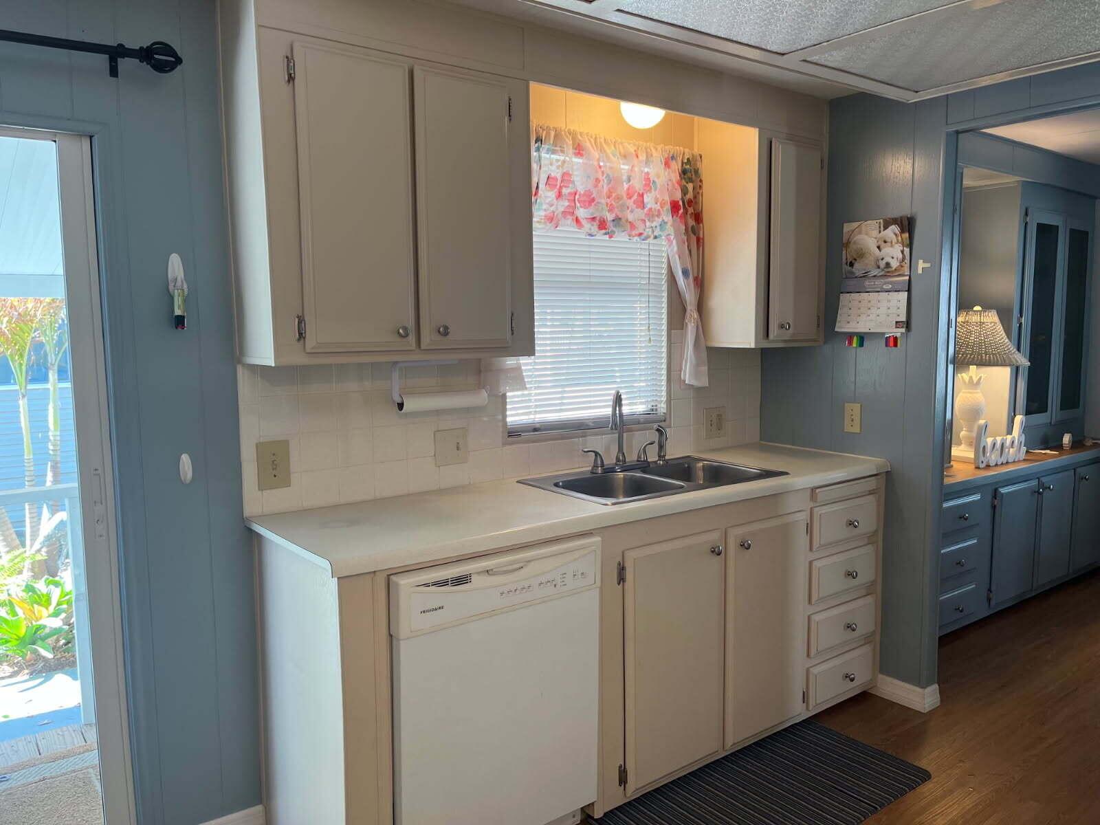 A kitchen features beige cabinets, white countertops, a stainless steel sink, and a white dishwasher — 304 Mockingbird Avenue, Fort Pierce FL 34982, FORT PIERCE, FL