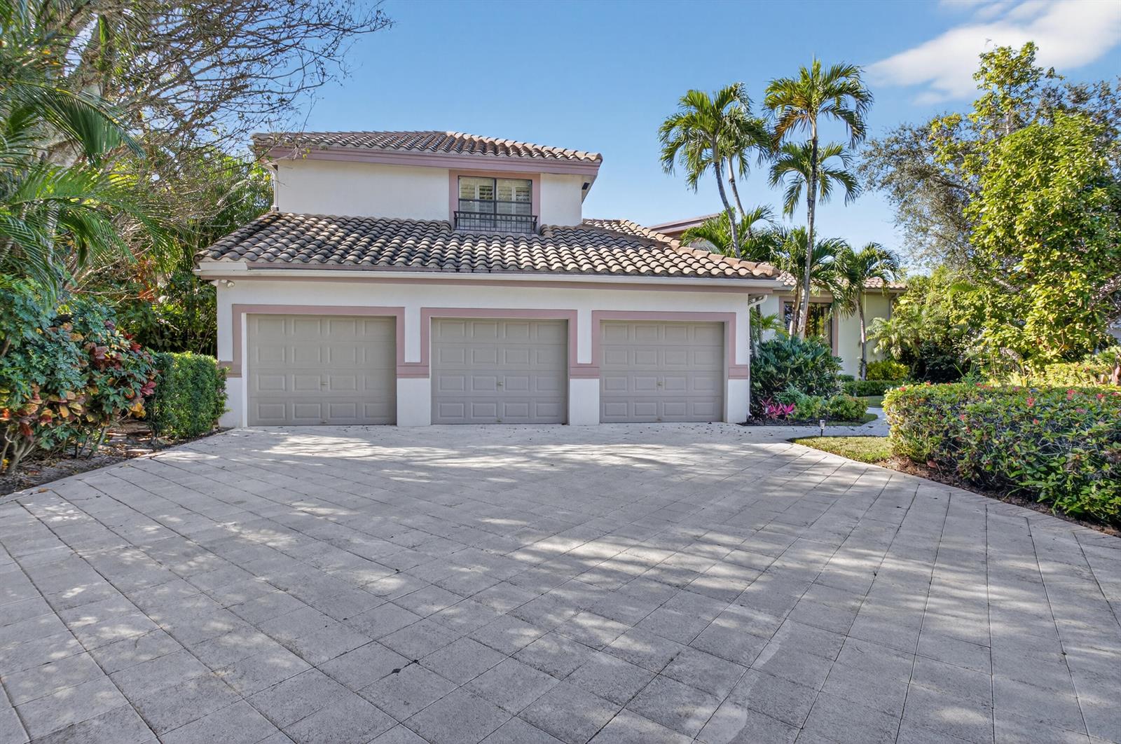 A three-car garage with a tiled roof and a paved driveway in front of a house — 2629 NW 64th Place, Boca Raton FL 33496, BOCA RATON, FL