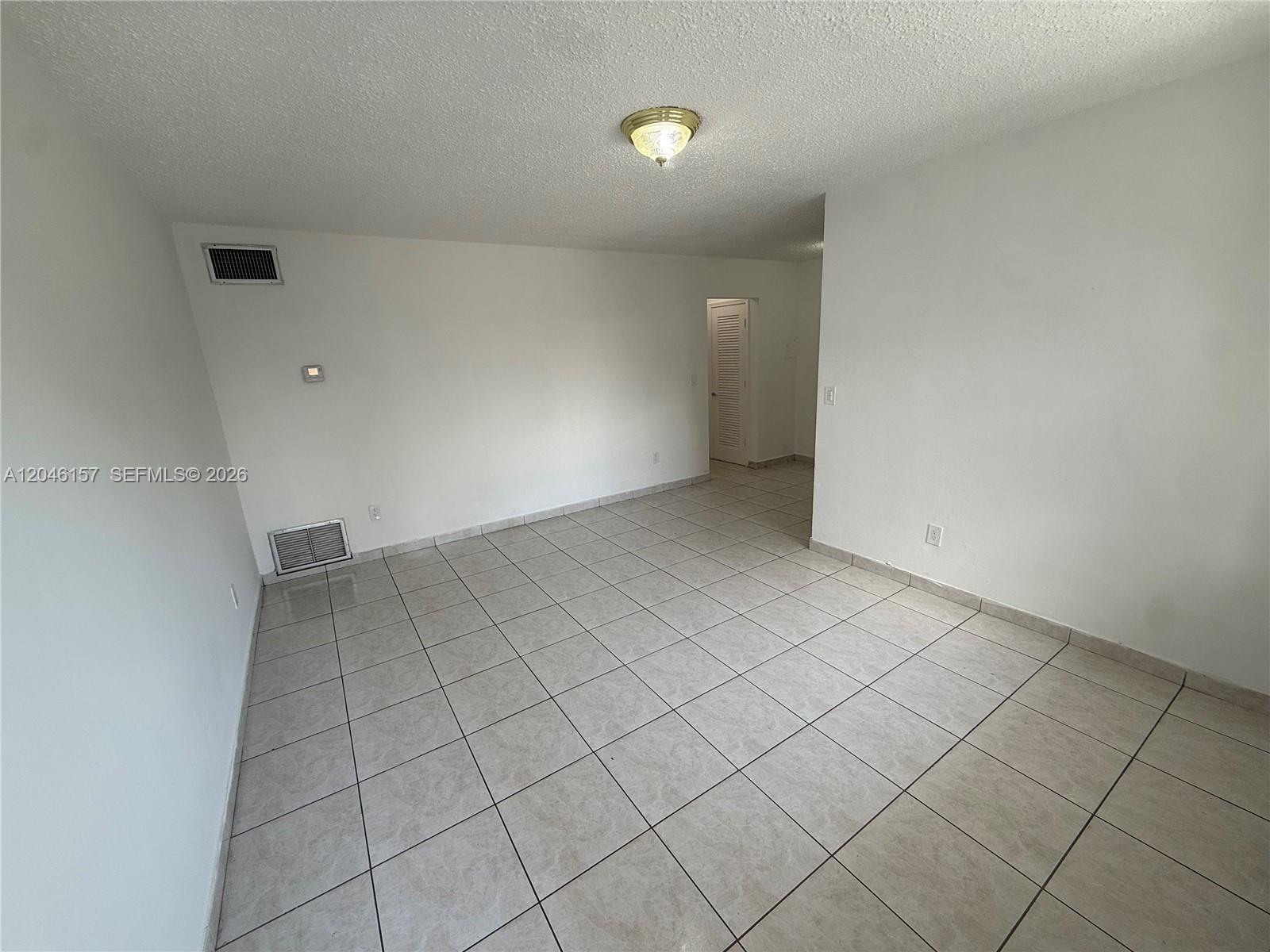 An empty room features white walls, a textured ceiling, and light-colored square floor tiles — 4651 W Flagler St # 36, Miami FL 33134, MIAMI, FL