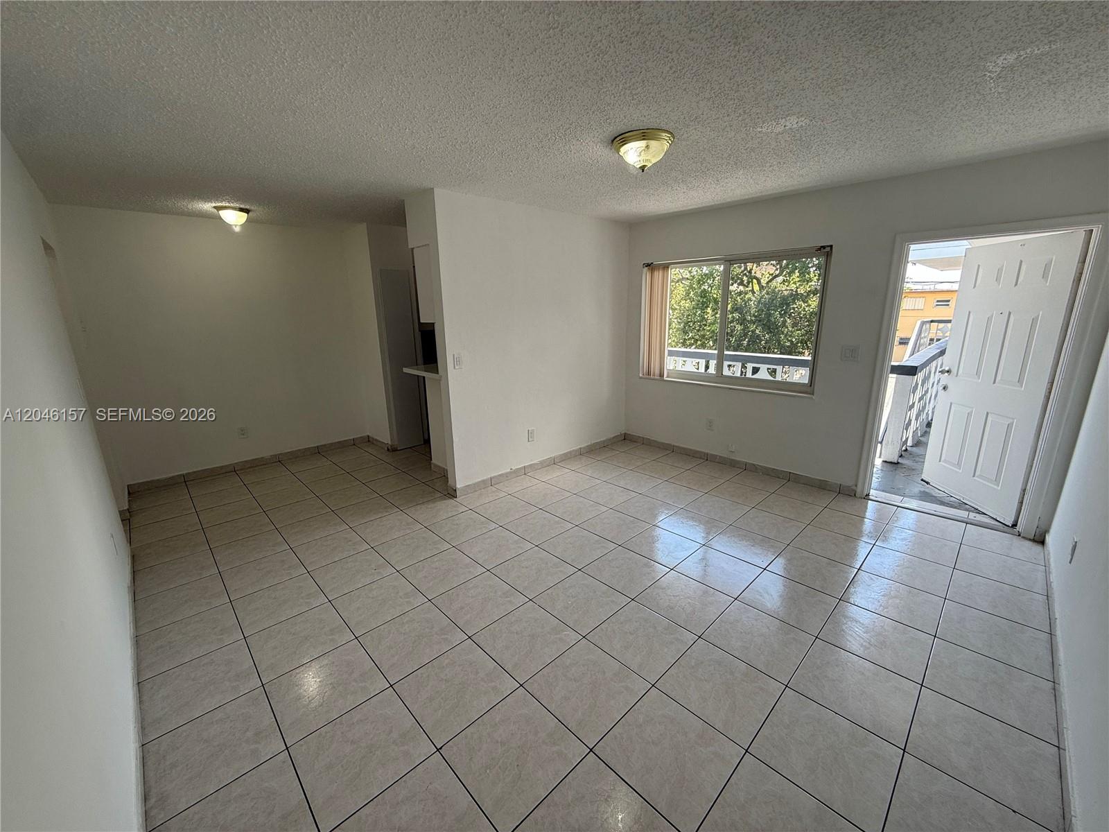 An empty room features white walls, tiled floors, a window, and an open exterior door — 4651 W Flagler St # 36, Miami FL 33134, MIAMI, FL