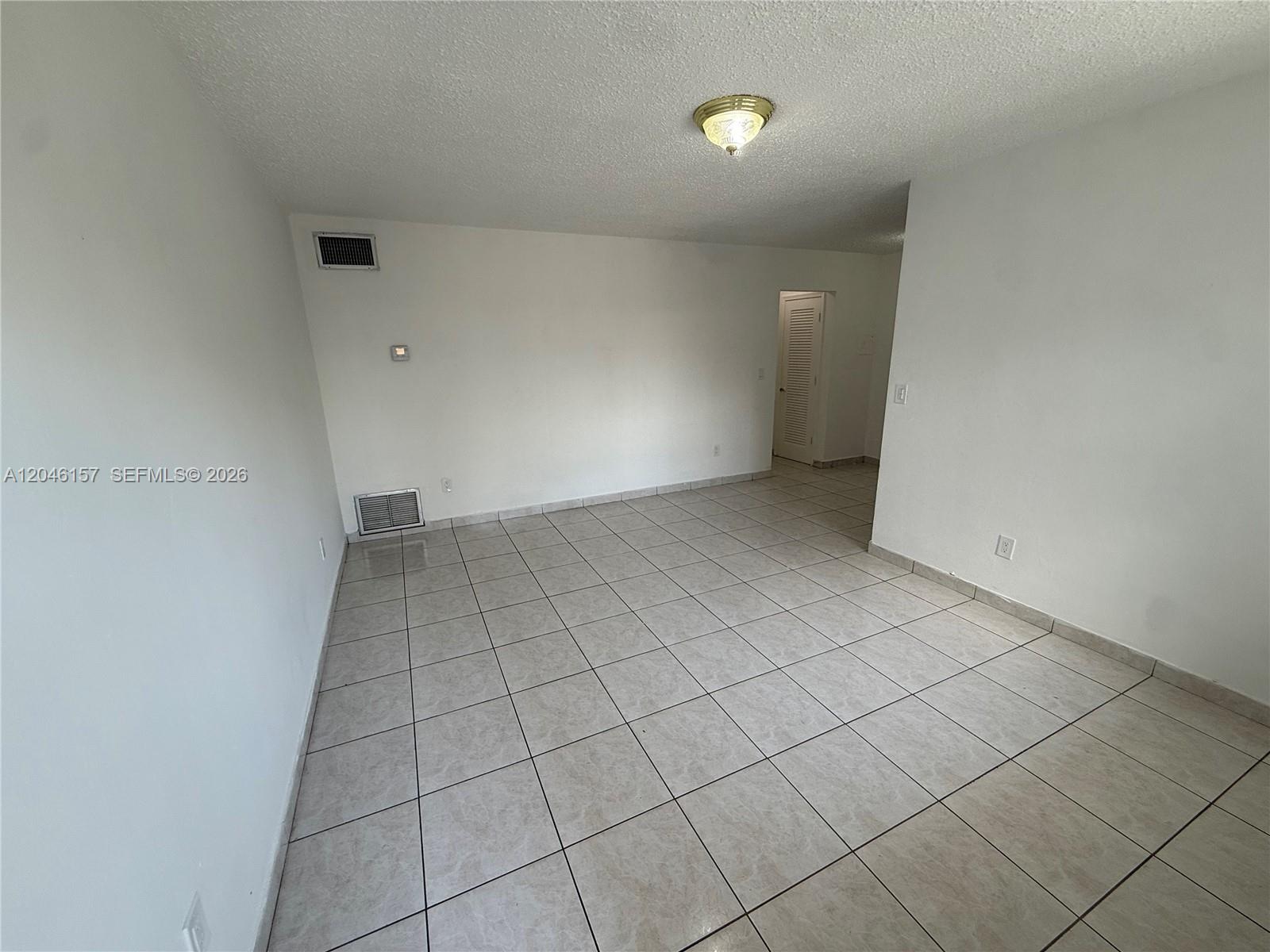An empty room features white walls, light-colored square floor tiles, and a ceiling light fixture — 4651 W Flagler St # 36, Miami FL 33134, MIAMI, FL