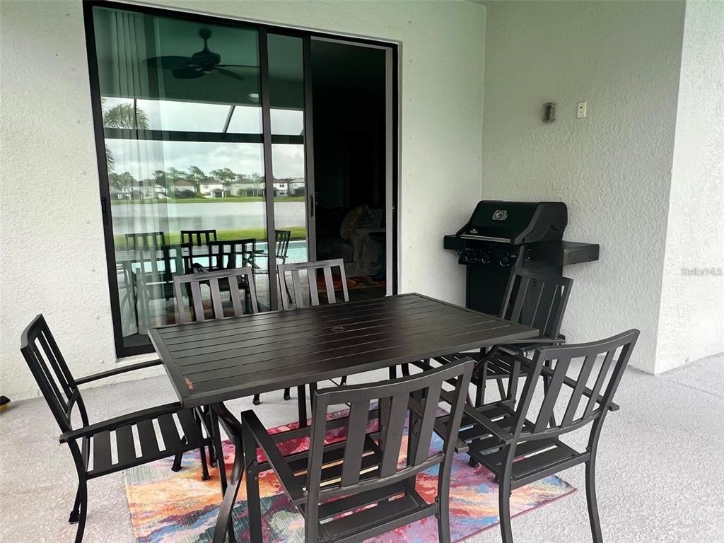 A covered patio features a dining table with chairs, a grill, and a sliding glass door — 6236 BAYWOOD COURT, LAKEWOOD RANCH, FL
