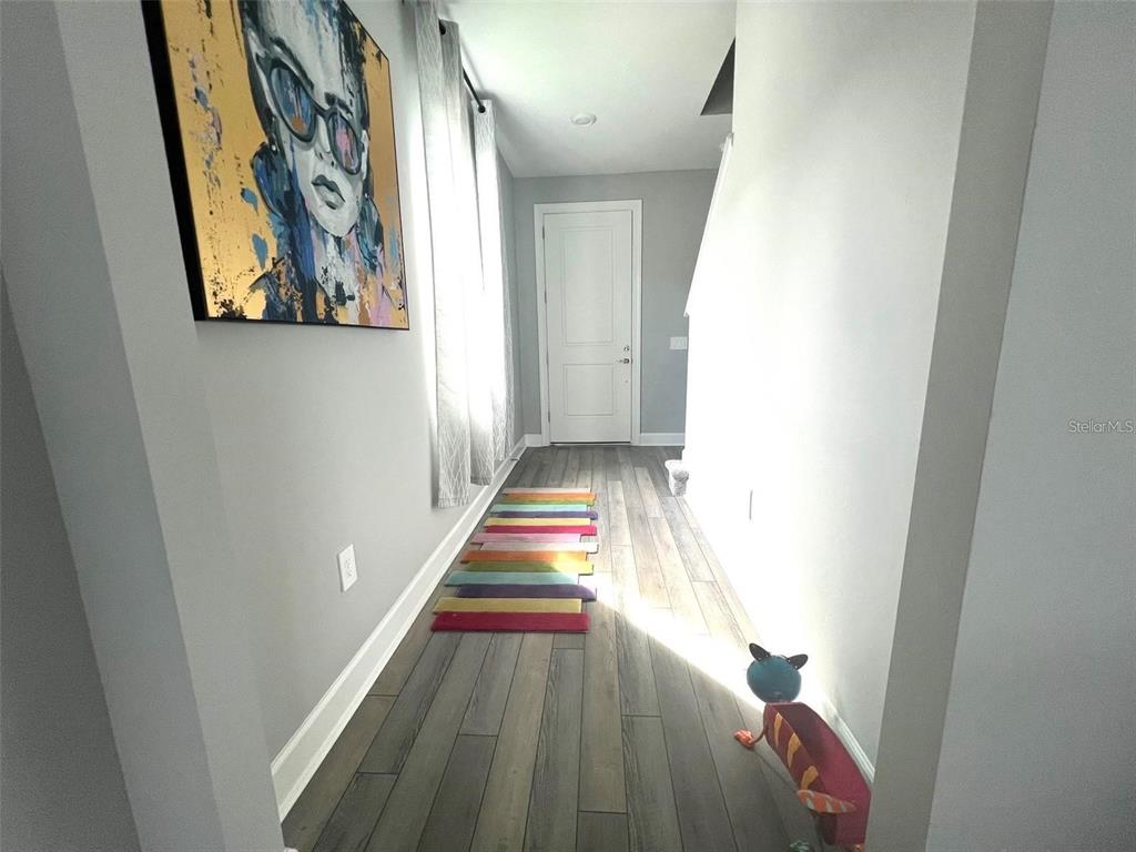 A hallway features gray walls, wood-look flooring, a colorful striped rug, and a piece of art — 6236 BAYWOOD COURT, LAKEWOOD RANCH, FL