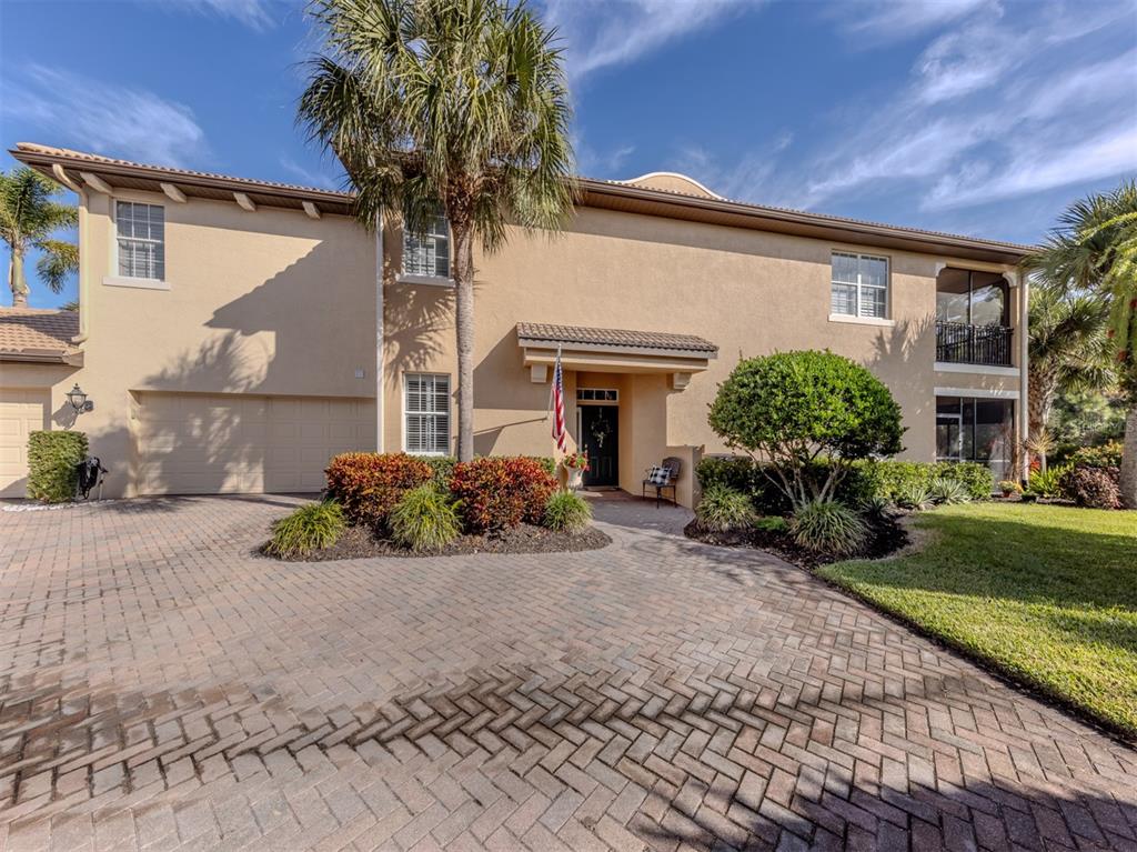 A two-story stucco house with a paved driveway, a palm tree, and a garage — 114 BELLA VISTA TERRACE UNIT 6B, NORTH VENICE, FL