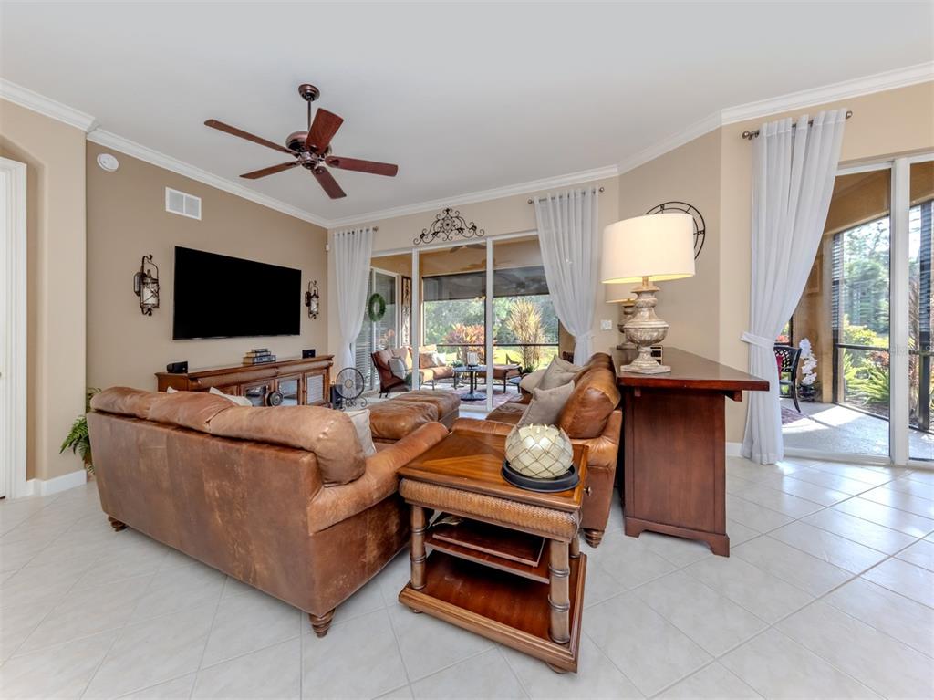 A living room features leather sofas, a television, and sliding glass doors leading to a patio — 114 BELLA VISTA TERRACE UNIT 6B, NORTH VENICE, FL